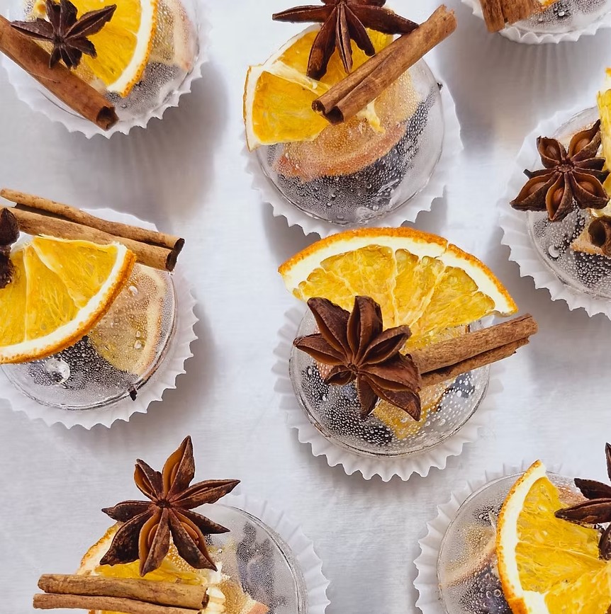 Several tea spheres with dried orange slices, cinnamon sticks and star anise seen from above