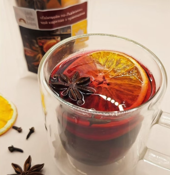 Glass mug of red spiced hibiscus tea with orange slice and star anise