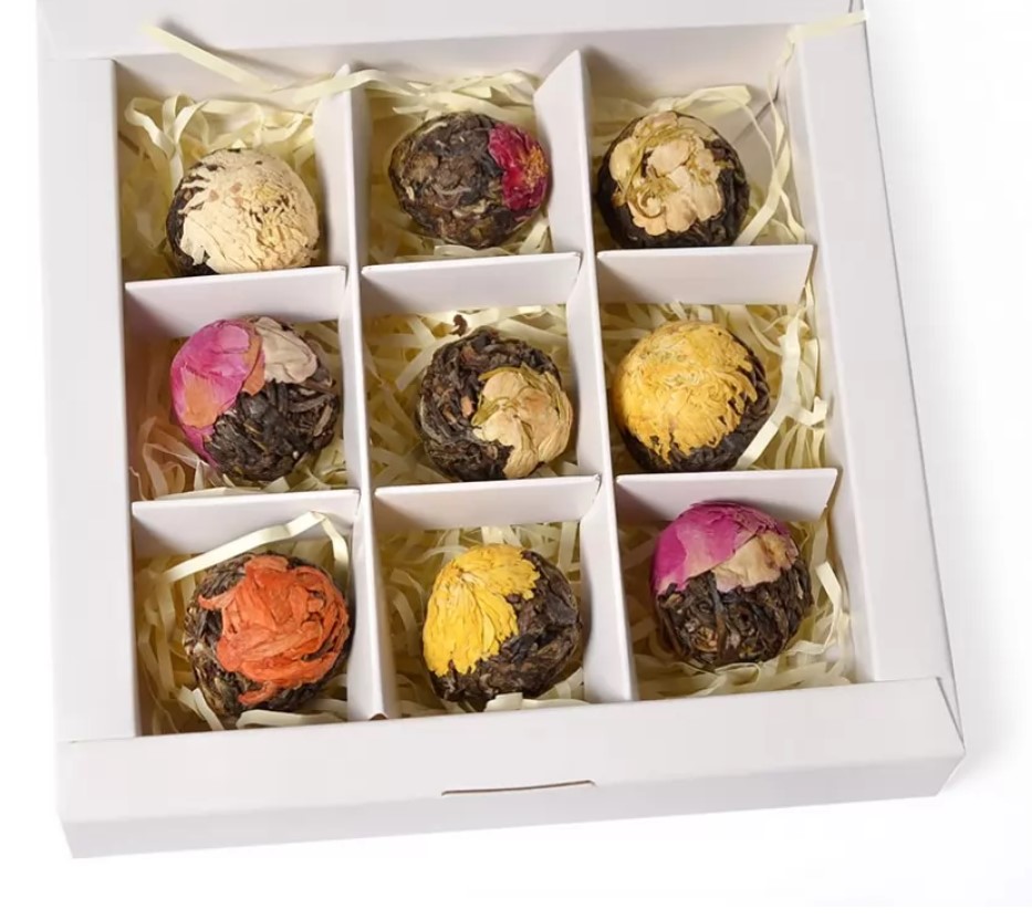 Nine blooming tea balls wrapped with rose, chrysanthemum and jasmine flowers in a partitioned box