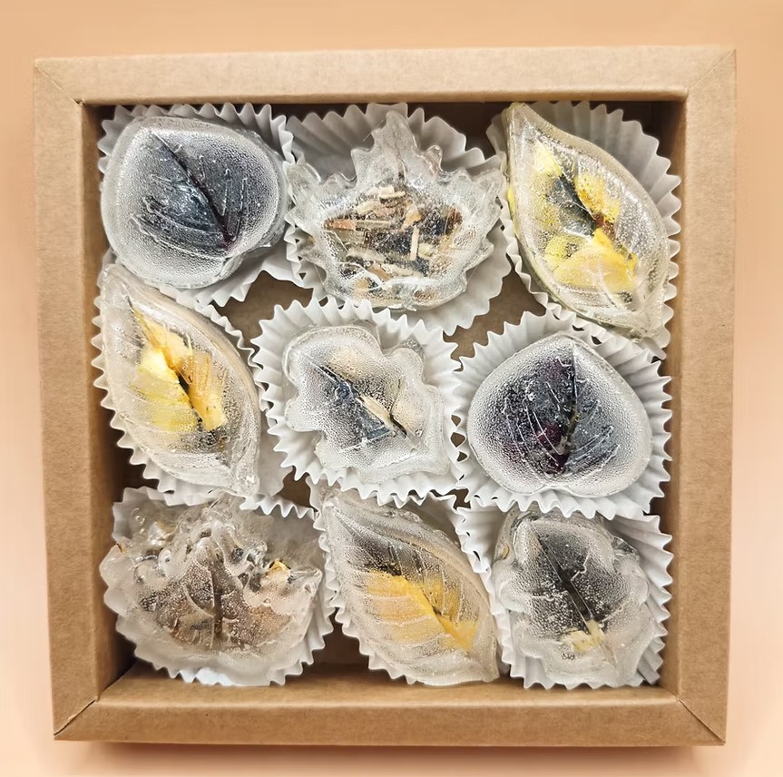 Kraft box with leaf-shaped tea pieces containing herbs and flower petals